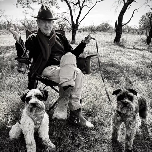 Black and white photo of Sam Baker and his two dogs.