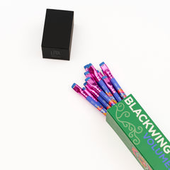 A set of colorful Blackwing Volume 143 pencils fanned out from a green box on a clean white background.