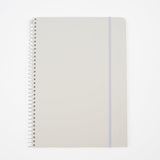 A large minimalist spiral-bound notebook by Blackwing with a white cover, a thin white elastic band, and a white wire coil binding, shown on a clean white background. It features a 'B' Blackwing emblem in the bottom-right corner.