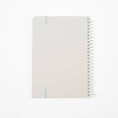 The back of a minimalist spiral-bound notebook by Blackwing with a white cover, a thin white elastic band, and a white wire coil binding, shown on a clean white background.