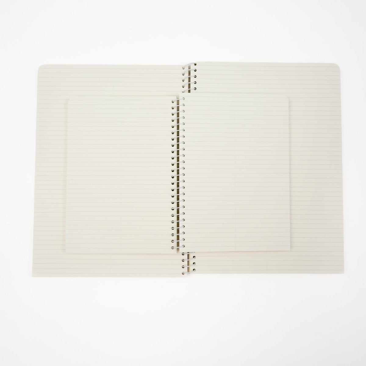 A stack of two open lined spiral notebooks with cream-colored pages and white metal wire binding, set against a plain white background.
