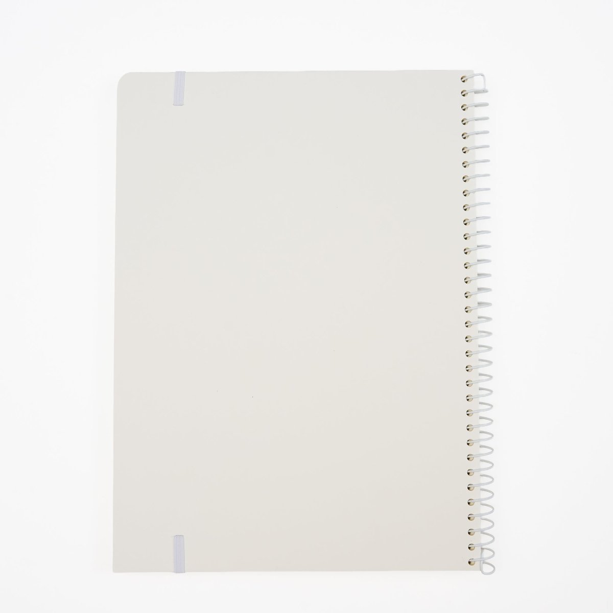 Back of a minimalist spiral-bound notebook by Blackwing with a white cover, a thin white elastic band, and a white wire coil binding, shown on a clean white background.