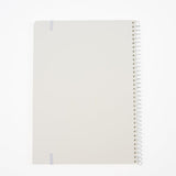 Back of a minimalist spiral-bound notebook by Blackwing with a white cover, a thin white elastic band, and a white wire coil binding, shown on a clean white background.