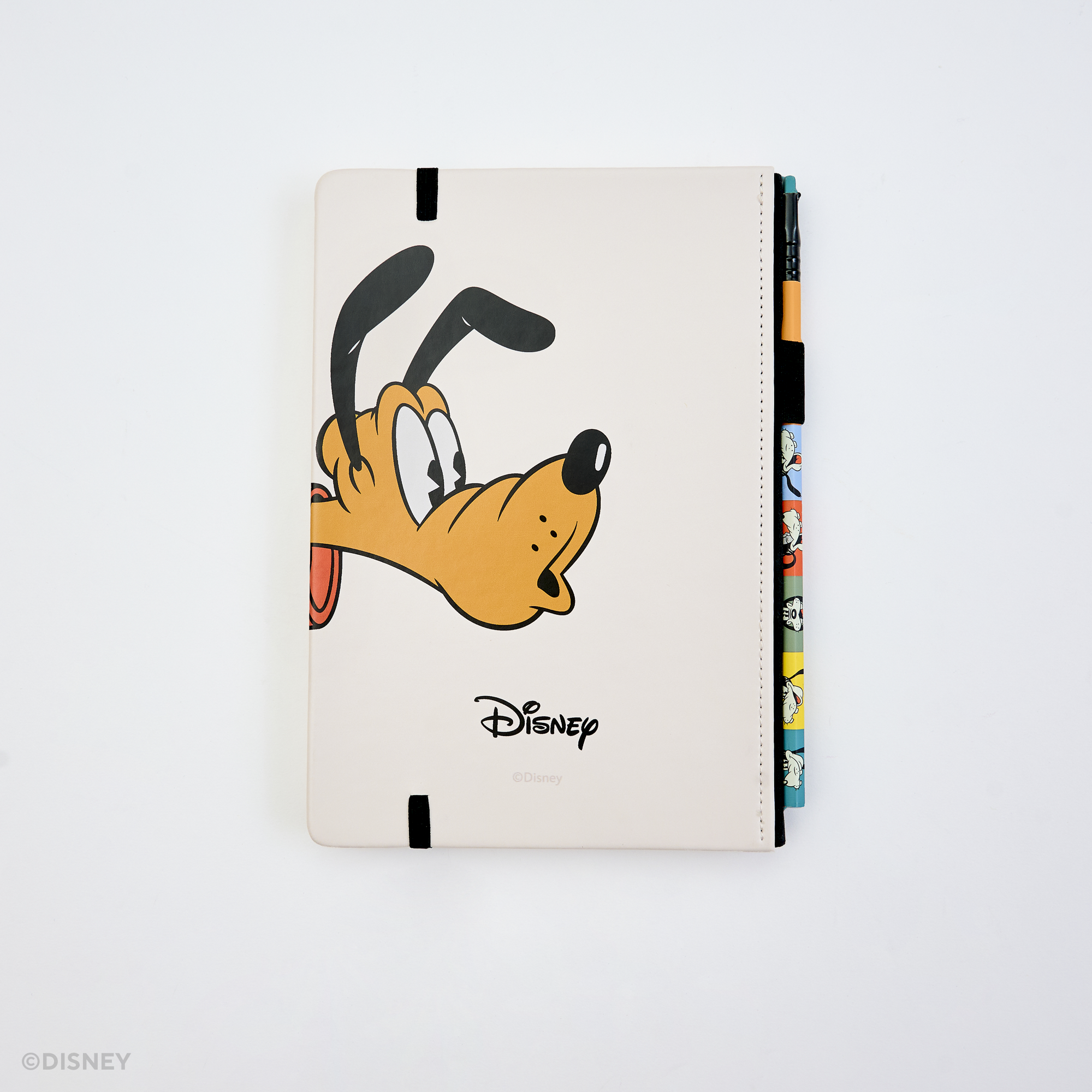 The back of a Disney hardcover notebook featuring a cartoon Pluto face with a black elastic closure. There is a colorful pencil tucked into the side, photographed on a clean white background.