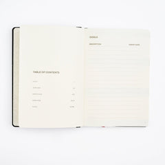 An open Blackwing planner showing two interior pages: a left page with a table of contents layout and a right page with lined goals and targets sections, photographed on a clean white background.