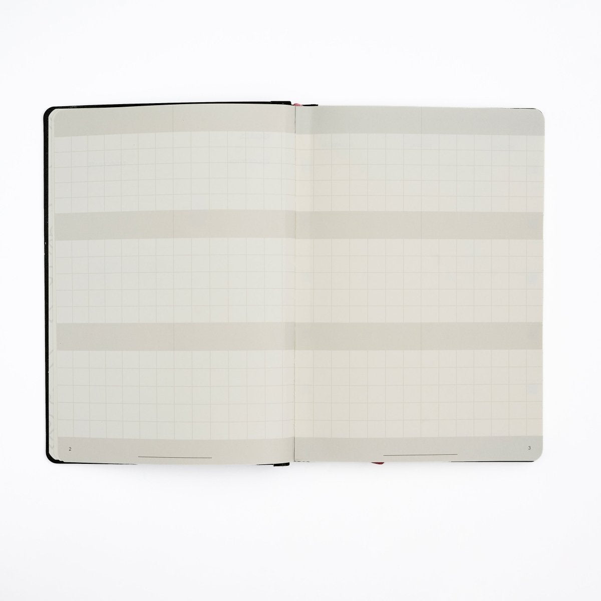 An open Blackwing Planner with blank grid-lined pages and horizontal gray bands, photographed flat against a clean white background.