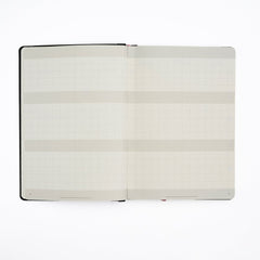 An open Blackwing Planner with blank grid-lined pages and horizontal gray bands, photographed flat against a clean white background.