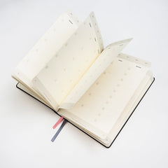 Blackwing Planner open with a fan of blank monthly view pages showing against a white background.